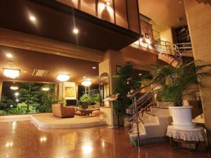都城市Miyakonojo Sun Plaza Hotel的大厅,在一座种植了盆栽植物的建筑里,有楼梯