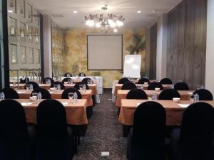 雅加达Couleur Hotel Cengkareng的一间会议室,配有桌椅和屏幕