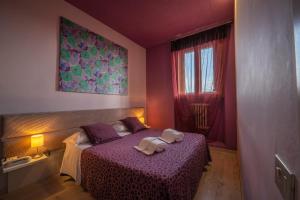 埃尔萨谷口村Hotel Palazzo Renieri - 3stelle S的一间卧室配有一张紫色床和两条毛巾