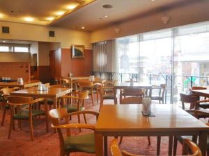 OshuMizusawa Grand Hotel的餐厅设有桌椅和大窗户。