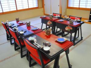 OniyanagimachiSenganishi Onsen Yumoto Azumakan的一间设有四张桌子和红色椅子的用餐室