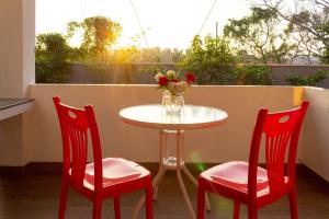 卡卢特勒Holiday Home Kalutara的阳台配有一张桌子和两把椅子以及一个带鲜花的花瓶