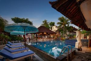 勒吉安Legian Village Hotel - CHSE Certified的度假村的游泳池配有蓝色椅子和遮阳伞