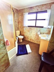 旺阿雷Denby Golf House Tikipunga的一间带卫生间、水槽和窗户的浴室