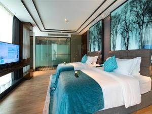 泸州Xana Hotelle·Hotel Luzhou Baizitu Square的一间卧室配有两张床和一台平面电视