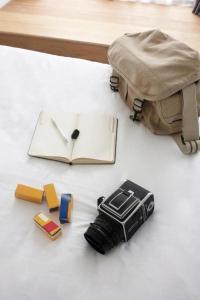 尖竹汶Rangsiya Boutique Hotel的一本书和装有照相机和其他物品的袋子