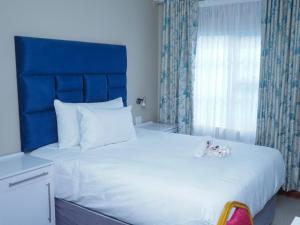 乌姆塔塔Elam Guest House的一间卧室配有一张白色大床和蓝色床头板