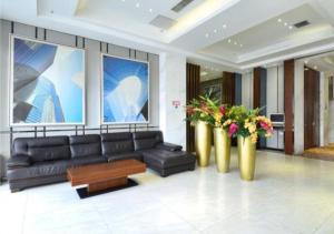 武汉City Comfort Inn Wuhan Tianhe Airport Julong Avenue Metro Station的客厅配有黑色真皮沙发和鲜花