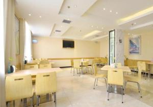 武汉City Comfort Inn Wuhan Tianhe Airport Julong Avenue Metro Station的一间带桌椅和电视的用餐室