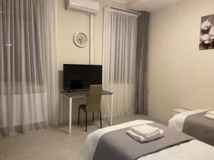 第比利斯Cultural Crossing Hotel的酒店客房配有书桌和电视。