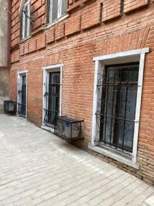第比利斯Cultural Crossing Hotel的红砖建筑,设有两扇窗户和一扇门