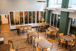 惠灵顿Haka House Wellington的餐厅设有木桌、椅子和窗户。