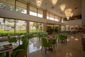 开罗Baron Hotel Cairo的餐厅设有绿色的椅子和桌子以及窗户。