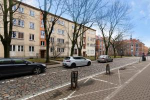 格但斯克Elite Apartments Podbielańska Center的2辆汽车停在大楼旁边的停车场