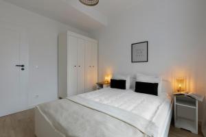 格但斯克Elite Apartments Podbielańska Center的白色卧室配有白色的床和两盏灯。