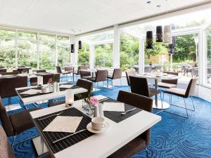 马斯特里赫特马斯特里赫特诺富特酒店的餐厅设有桌椅和窗户。