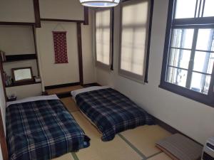 高山Guesthouse Tomaru的带两张床和两个窗户的房间
