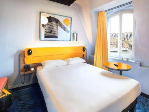 圣马洛宜必思时尚历史圣马洛中心酒店的一间卧室配有一张带黄色床头板的床和窗户