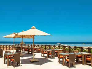 库塞尔Novotel Marsa Alam Beach Resort的海滩上设有桌椅和遮阳伞