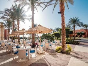 库塞尔Novotel Marsa Alam Beach Resort的一间设有椅子和遮阳伞及棕榈树的餐厅