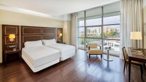 巴达霍斯NH埃斯特雷马杜拉赌场大酒店的卧室配有一张白色大床和一张书桌
