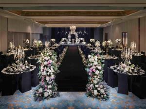 首尔Hotel Naru Seoul MGallery Ambassador的宴会厅配有带鲜花和吊灯的桌子