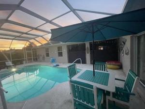 棕榈海岸Guest house withl kitchen living room 65" tv solar heated pool的一个带桌子和遮阳伞的游泳池