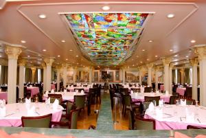 阿斯旺Nile Cruise Luxor Aswan 3,4 and 7 nights的一间带桌椅的用餐室和彩色玻璃天花板