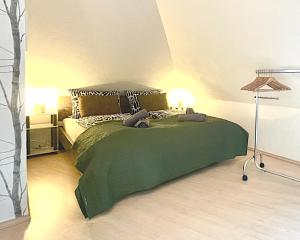 BurbachFemo SCHICK-modern, Natur, Rothaarsteig, 2Etg, 2Bäder的一间卧室,配有一张绿床,上面有两只填充动物