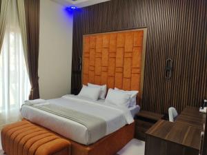 NnewiPassready Hotel and Suites Nnewi的一间卧室配有一张大床和木制床头板