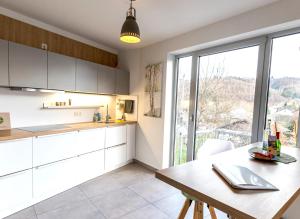 BurbachFemo SCHICK-modern, Natur, Rothaarsteig, 2Etg, 2Bäder的厨房配有白色橱柜、桌子和窗户。