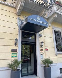 米兰Hotel Florence Milano的建筑前有两株盆栽植物的酒店入口