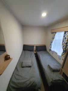 Lytchett MinsterEscape City Caravan的小房间设有两张床和窗户