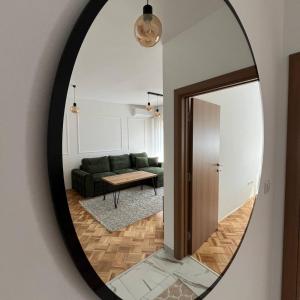ŽiviniceZARA Apartman Živinice的镜子反射着带绿色沙发的客厅