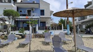 内亚卡瓦里Bebas Apartments Nea Karvali的海滩上的一组椅子和一把遮阳伞