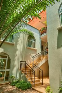 基加利Nobilis Hotel and Apartments的房屋前方有楼梯和棕榈树