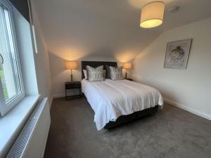 邓博因Modern Dunboyne Home的卧室配有一张带白色床单和枕头的大床。