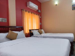 蓬蒂切里Guru Residency Pondicherry的红色墙壁客房的两张床