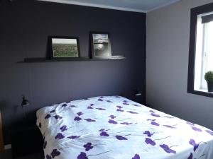 Ytre KibergFeriehus ved Barentshavet - Holiday home by the Barents Sea的一间卧室,床上有紫色鲜花
