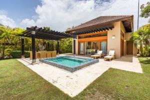 蓬塔卡纳Newly added Tropical Bungalow at Green Village的一个带游泳池和房子的后院