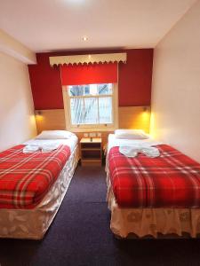伦敦Carlton Hotel的宿舍间的两张床,设有红色的墙壁和窗户。