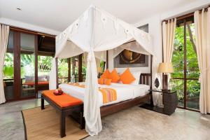 涛岛Ban's Diving Resort SHA Extra Plus的一间卧室配有带橙色枕头的天蓬床