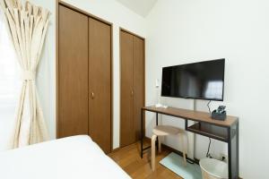 福冈Rooms箱崎的一间卧室配有一张桌子、一台电视和一张床