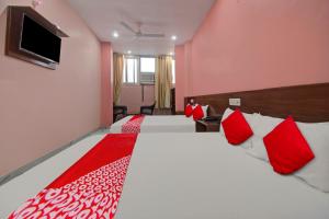 斋浦尔Hotel Rameshwaram的一间卧室配有两张带红白色枕头的床