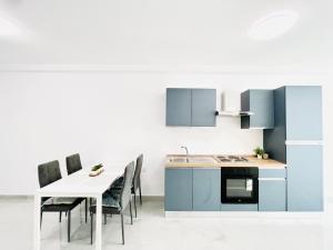 姆西达SUNSHINE SUITS - BRAND NEW APARTMENTS的厨房配有蓝色橱柜和桌椅