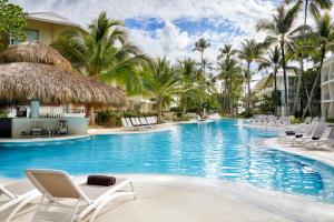 蓬塔卡纳Impressive Premium Punta Cana - All Inclusive的度假村的游泳池,设有躺椅和棕榈树