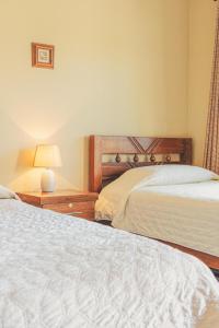 TorotoroHostal Claure的一间卧室设有两张床和一张桌子上的台灯。