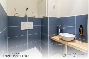 巴黎Beauquartier - Marais, Pastourelle的浴室铺有蓝色瓷砖,在柜台上设有水槽