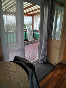 加斯泰MOBIL HOME 43 dans Camping 4 Etoiles的一间卧室设有一扇门,可通往一个带椅子的甲板
