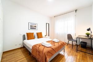 布拉加Flat Armada II - Apartamento T5 junto ao BragaParque的一间卧室配有一张带桌子和椅子的床